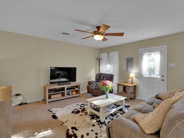 living area featuring electric panel, baseboards, visible vents, a ceiling fan, and tile patterned flooring