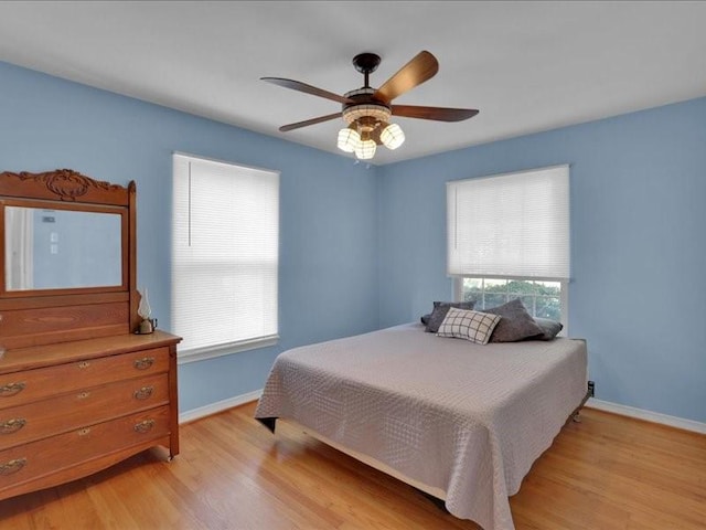 bedroom with ceiling fan, light wood-style flooring, and baseboards