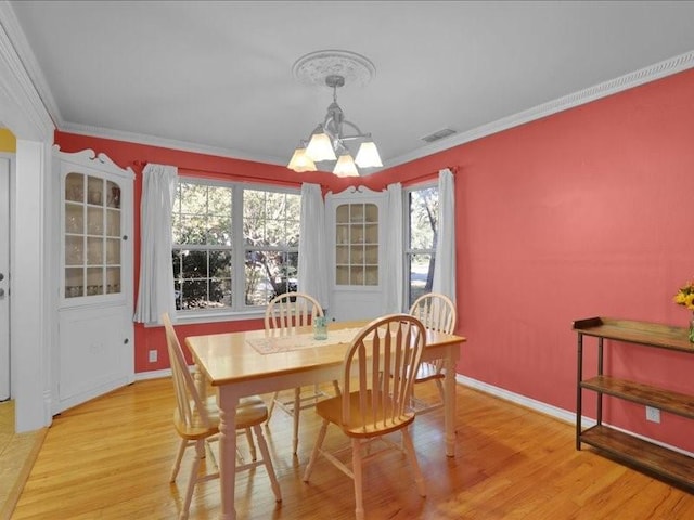 dining area with ornamental molding, a notable chandelier, light wood-style flooring, and baseboards