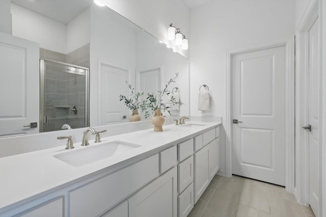 bathroom with tile patterned floors, a sink, a shower stall, and double vanity