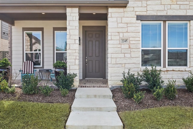 entrance to property with stone siding and a porch