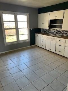 kitchen featuring baseboards, tasteful backsplash, dark countertops, and white cabinets