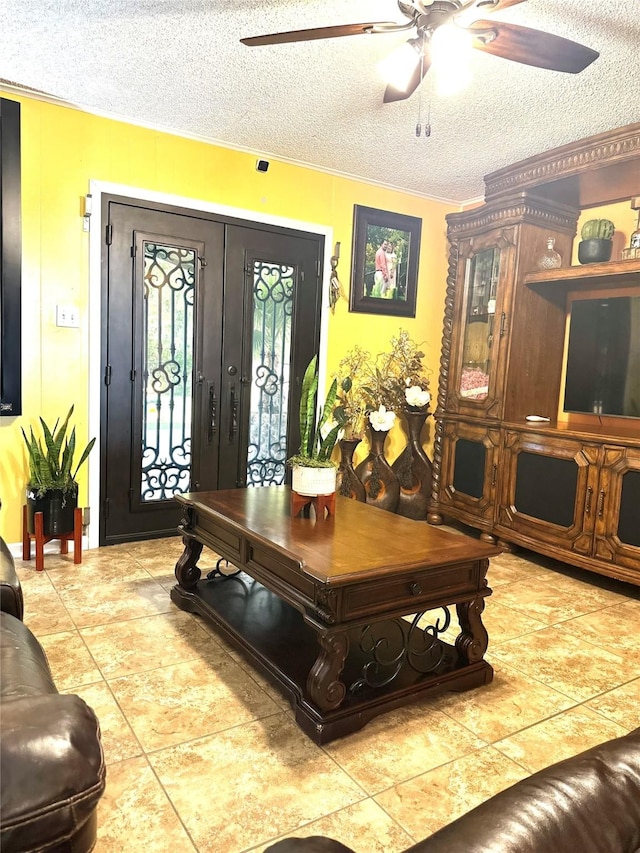 tiled living area with a textured ceiling, ceiling fan, and french doors