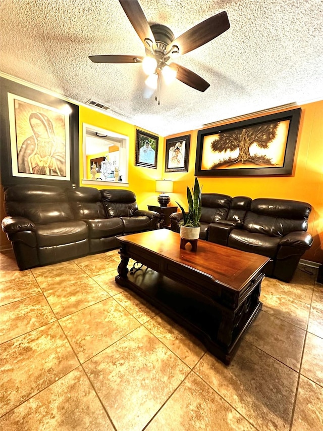 living room with a ceiling fan, tile patterned flooring, visible vents, and a textured ceiling