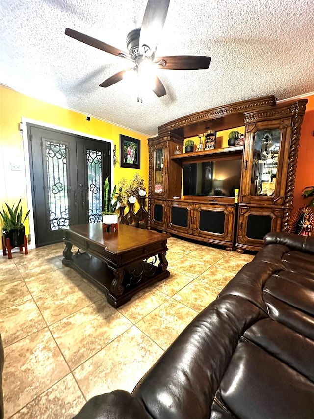 tiled living area with ceiling fan, a textured ceiling, and french doors