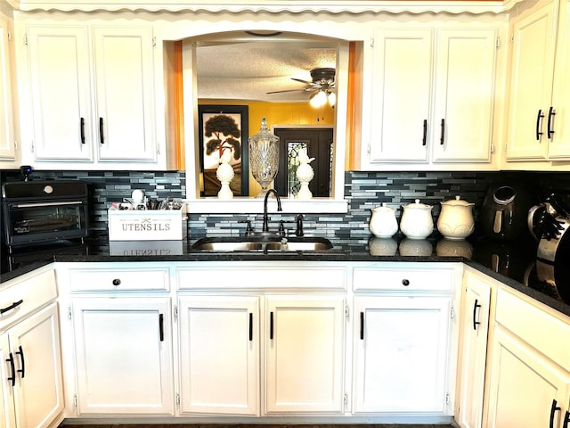 kitchen featuring ceiling fan, white cabinetry, decorative backsplash, and a sink