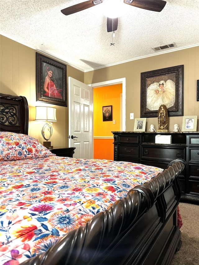 carpeted bedroom with a ceiling fan, crown molding, visible vents, and a textured ceiling