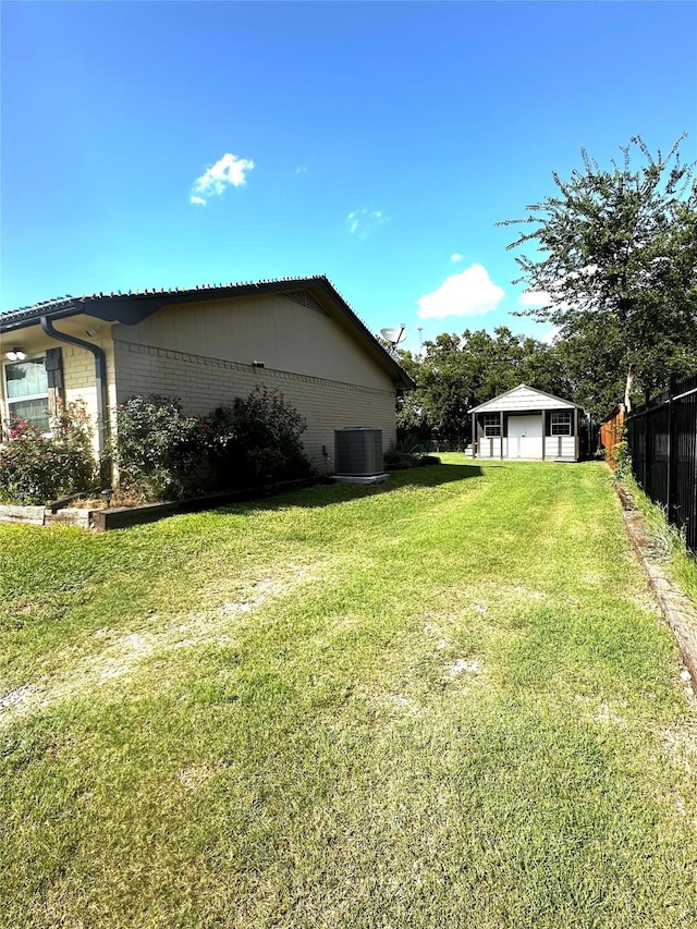 view of yard with fence, an outdoor structure, and central AC unit