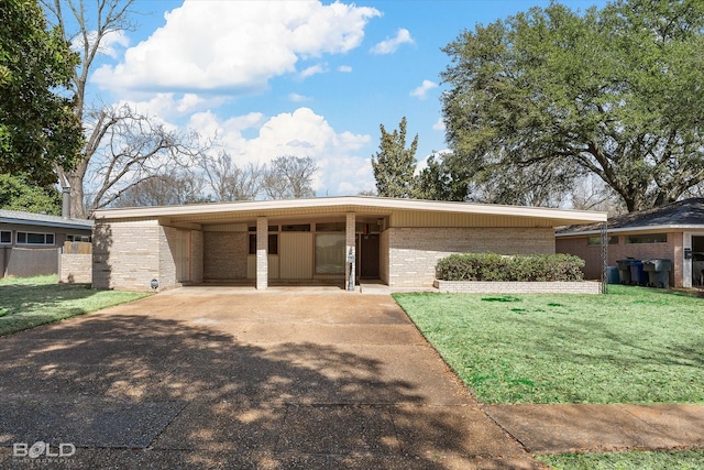 mid-century inspired home featuring an attached carport, brick siding, fence, driveway, and a front lawn