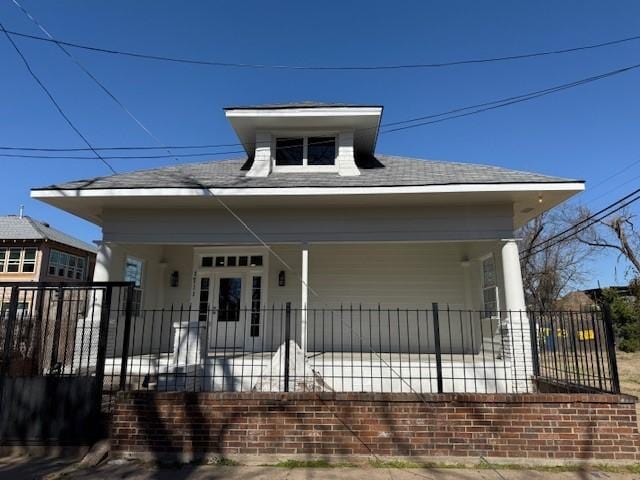 view of front of house with a shingled roof and a fenced front yard