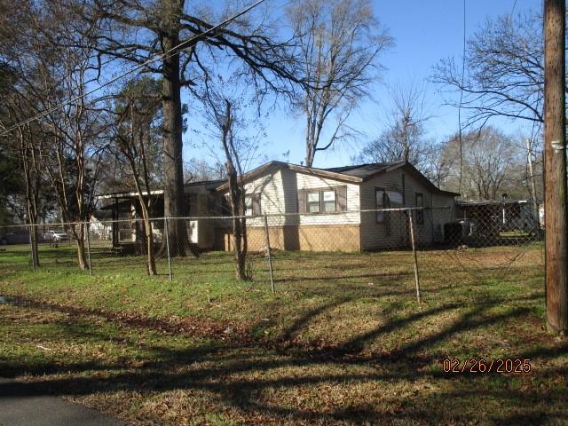 view of property exterior featuring fence and a lawn