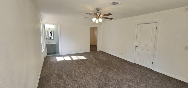 unfurnished bedroom with dark colored carpet, visible vents, a ceiling fan, connected bathroom, and baseboards