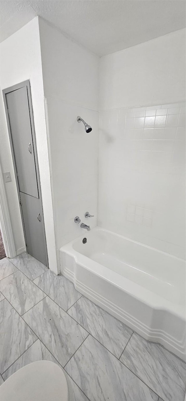 full bathroom featuring marble finish floor, shower / bath combination, and a textured ceiling