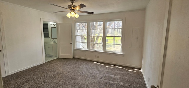 unfurnished room featuring a sink, a ceiling fan, baseboards, dark colored carpet, and crown molding