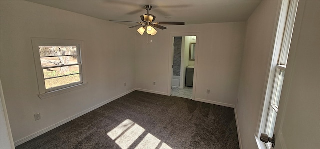 spare room with ceiling fan, baseboards, and dark colored carpet