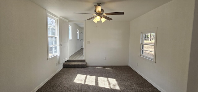 empty room with dark carpet, a ceiling fan, and baseboards