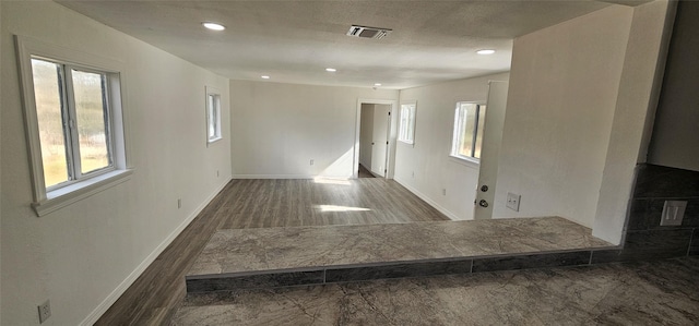 spare room featuring recessed lighting, wood finished floors, visible vents, and baseboards