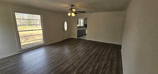 spare room with dark wood-style floors, a sink, a ceiling fan, and baseboards