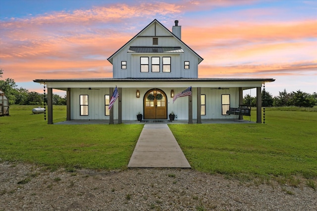 modern farmhouse featuring a chimney, board and batten siding, a front yard, and a ceiling fan