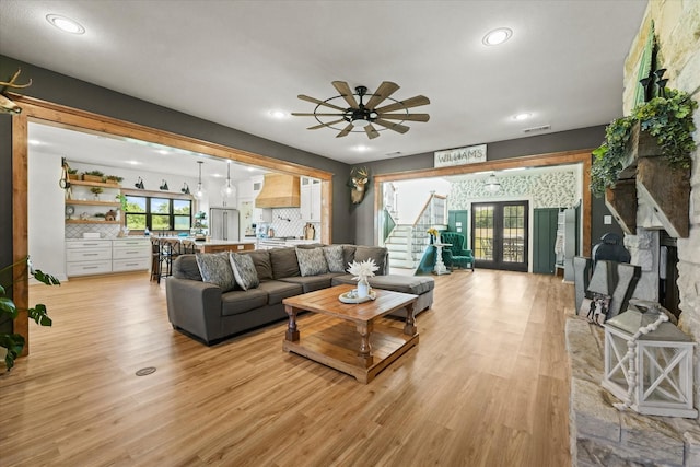 living room featuring light wood finished floors, stairway, visible vents, and french doors