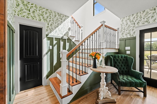 foyer entrance with stairway, wood finished floors, and wallpapered walls