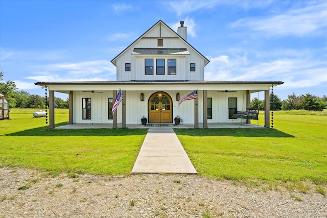 modern farmhouse style home with board and batten siding, a front yard, ceiling fan, and a chimney