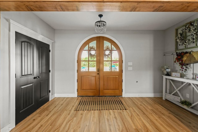 foyer entrance with arched walkways, french doors, light wood-style flooring, and baseboards