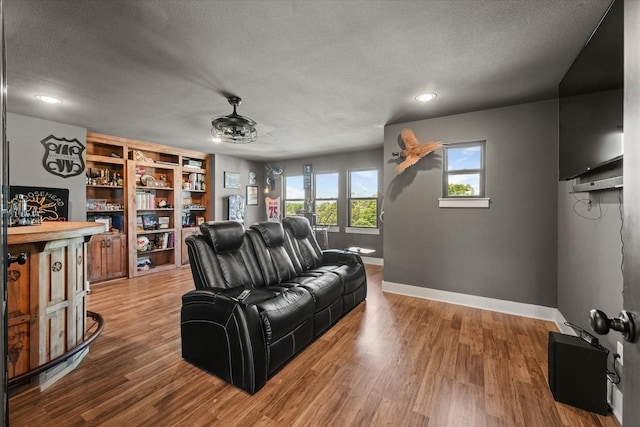 living area with a textured ceiling, wood finished floors, and baseboards