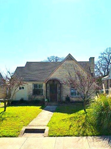 view of front of house with stone siding, a chimney, and a front lawn