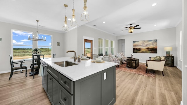 kitchen featuring light wood finished floors, ornamental molding, gray cabinets, light countertops, and a sink