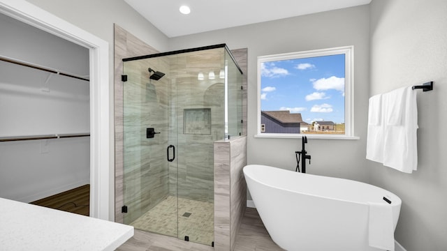 full bath with a freestanding tub, a shower stall, baseboards, and a spacious closet