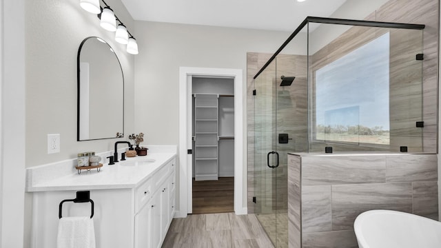 full bathroom with a stall shower, a freestanding tub, vanity, and a spacious closet