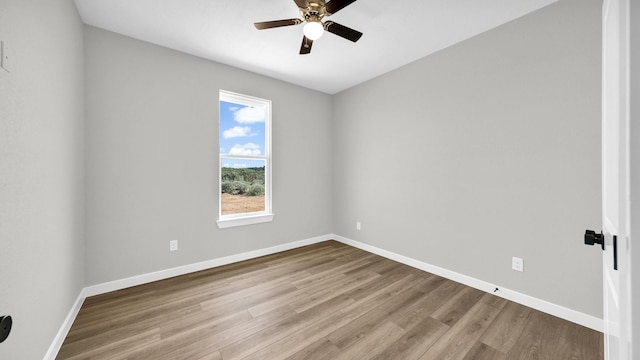 empty room with wood finished floors, a ceiling fan, and baseboards