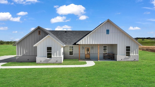 modern farmhouse featuring roof with shingles, brick siding, board and batten siding, and a front lawn