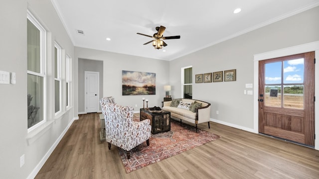 living room featuring visible vents, baseboards, wood finished floors, and ornamental molding