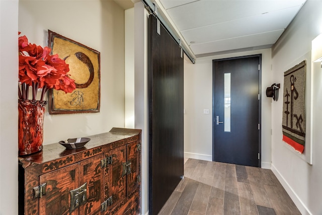 hallway with dark wood-style floors, a barn door, elevator, and baseboards