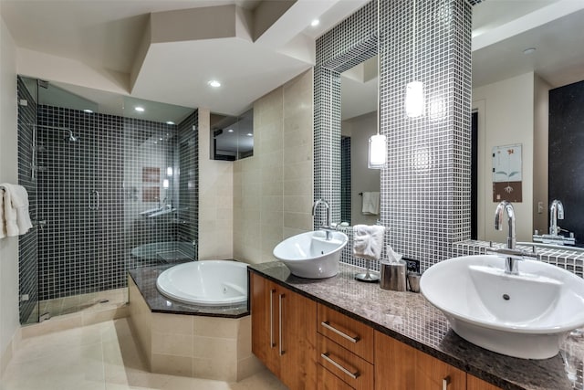 bathroom with tile walls, a sink, a jetted tub, and a walk in shower