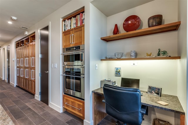 office featuring wood tiled floor, visible vents, and built in study area