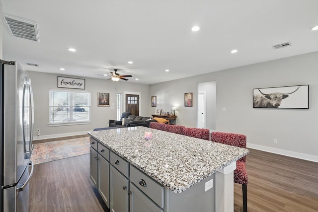 kitchen with dark wood-style floors, freestanding refrigerator, gray cabinets, and visible vents