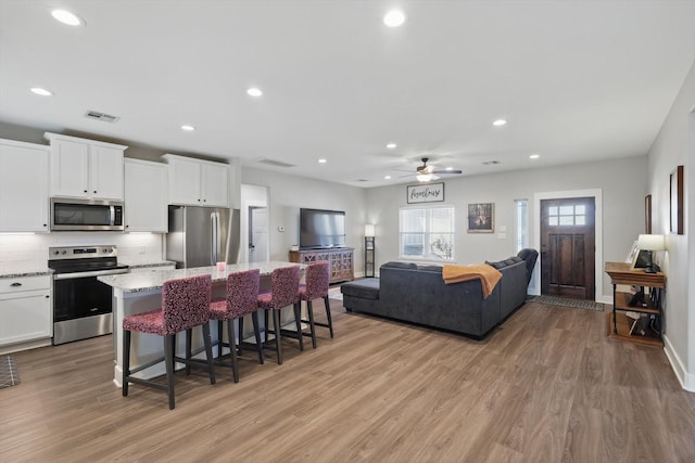 kitchen featuring stainless steel appliances, light wood-style floors, visible vents, and a center island