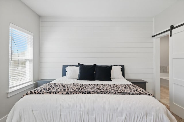 bedroom featuring a barn door and wooden walls