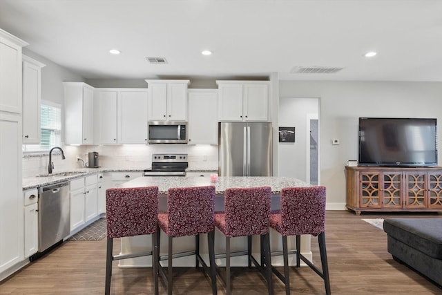 kitchen featuring tasteful backsplash, visible vents, appliances with stainless steel finishes, white cabinetry, and a sink