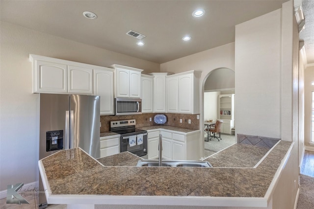 kitchen featuring visible vents, arched walkways, tile countertops, stainless steel appliances, and a sink