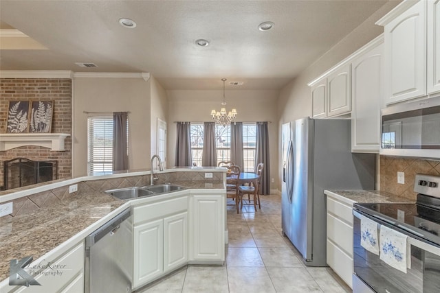 kitchen featuring visible vents, decorative backsplash, stainless steel appliances, a fireplace, and a sink