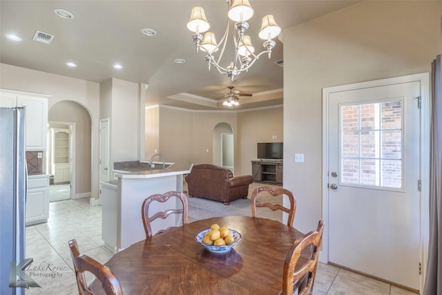 dining room featuring arched walkways, a tray ceiling, light tile patterned floors, visible vents, and ceiling fan with notable chandelier