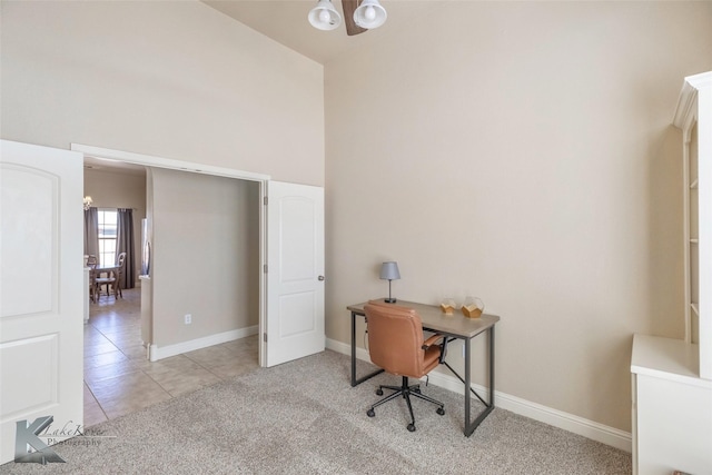 home office with baseboards, a high ceiling, light tile patterned flooring, and light colored carpet