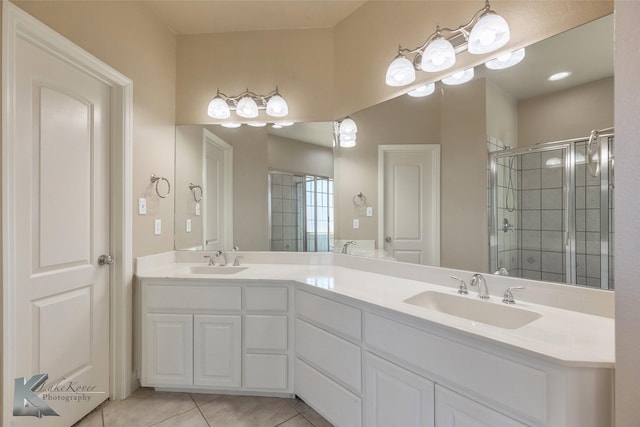 full bathroom with double vanity, a stall shower, a sink, and tile patterned floors