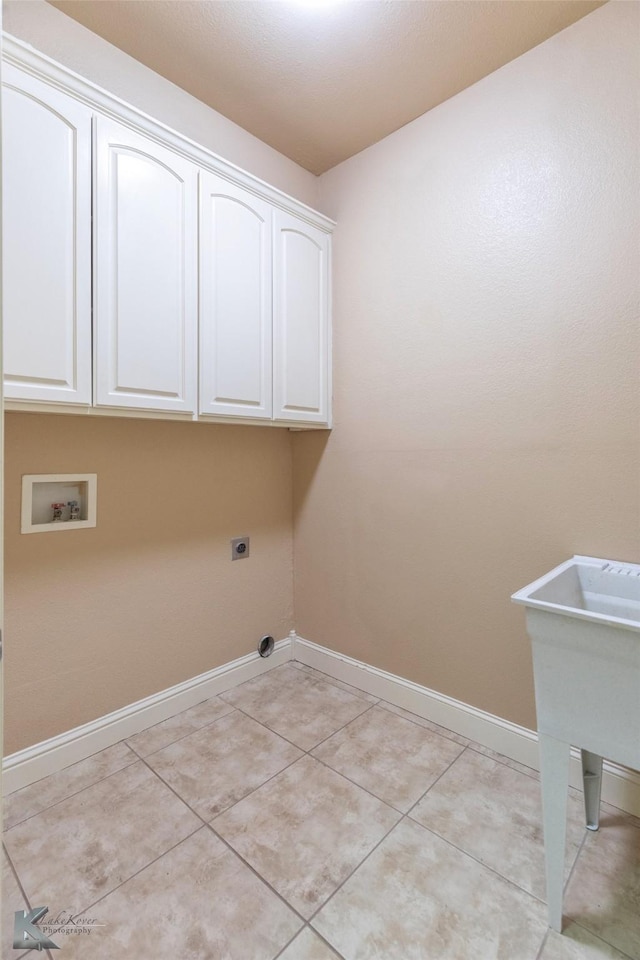 laundry room featuring cabinet space, baseboards, hookup for an electric dryer, washer hookup, and light tile patterned flooring