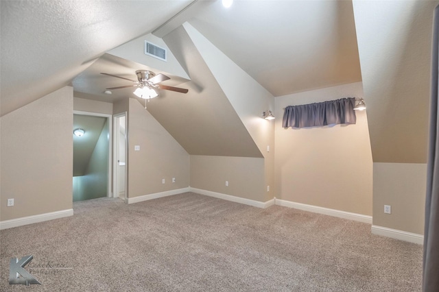 additional living space with baseboards, visible vents, vaulted ceiling, and carpet flooring