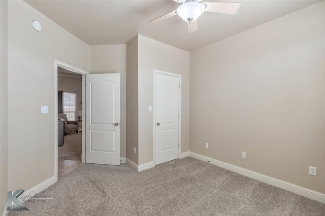 unfurnished bedroom featuring carpet floors, baseboards, and a ceiling fan